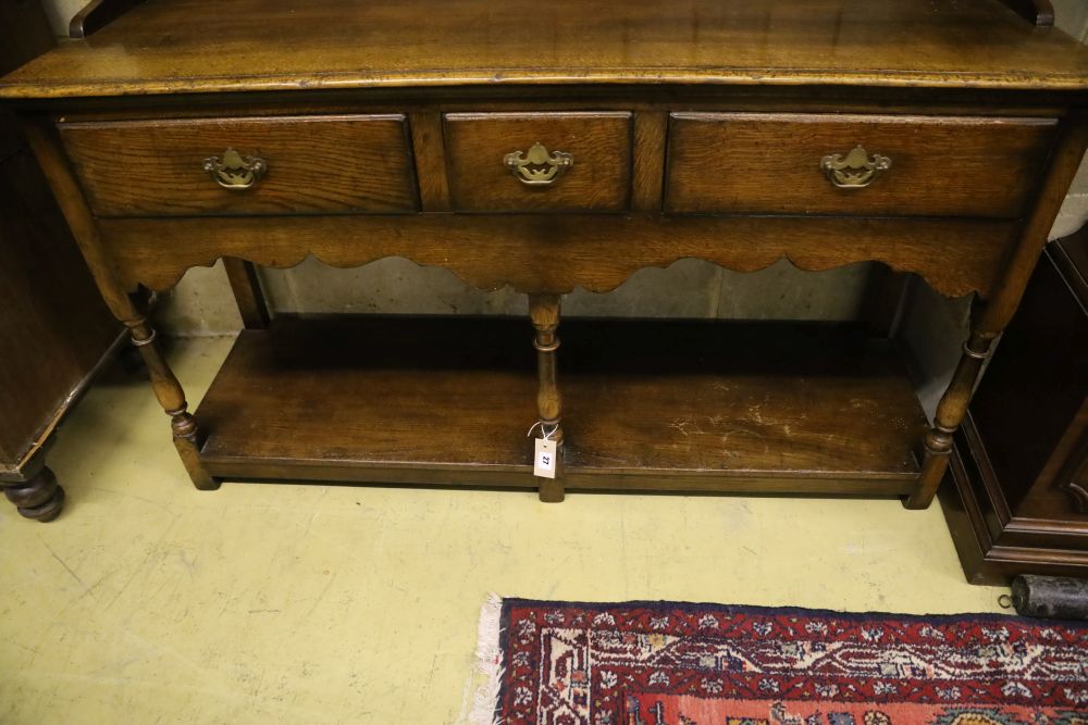 A small Georgian style reproduction oak dresser, having shelved boarded back, shaped apron and pot shelf, width 137cm, depth 44cm, heig